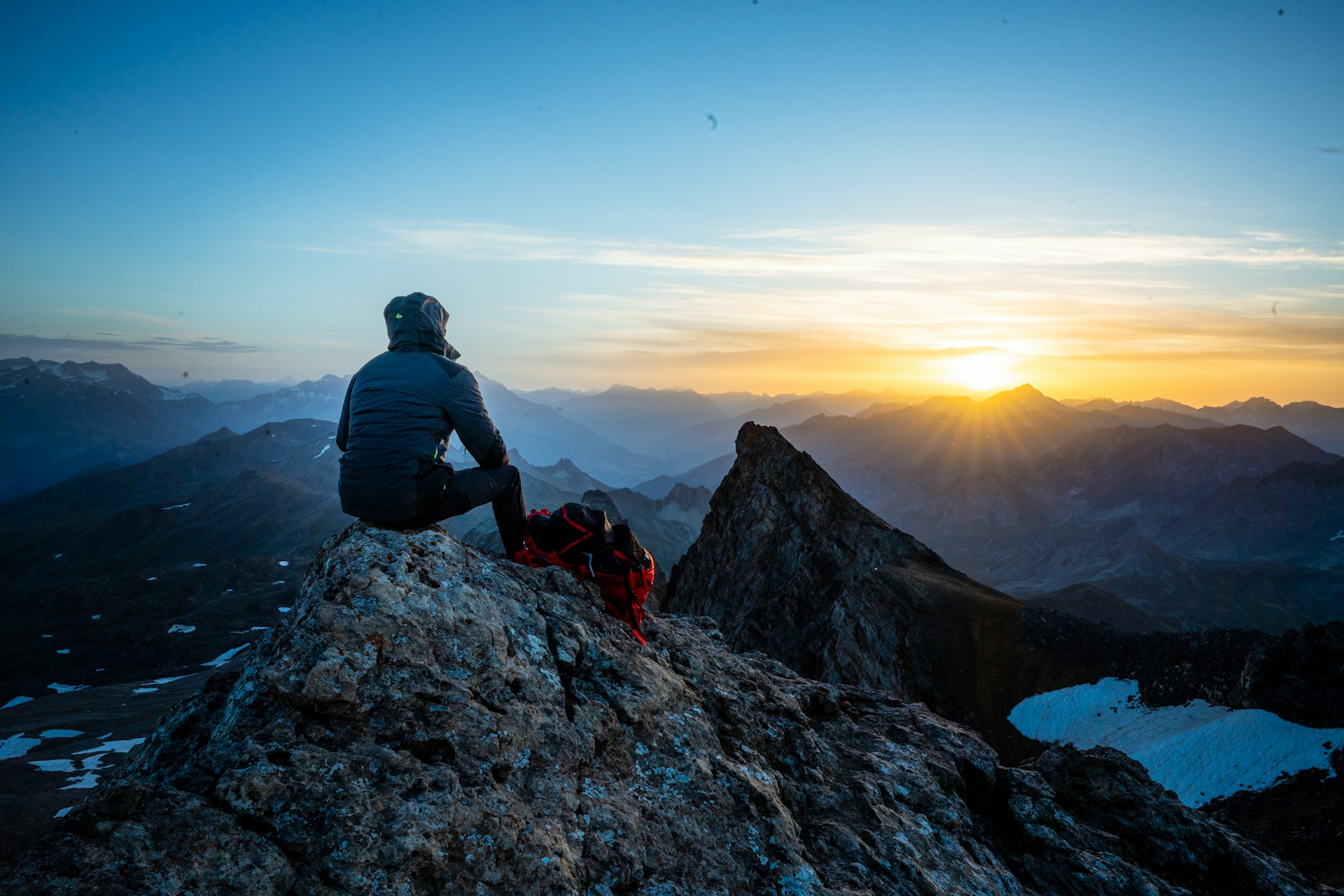 A lone hiker standing in the mountains under sunlight, taking in the view